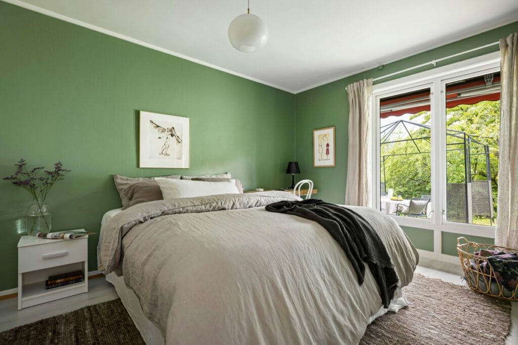 Saliegroene muur in een slaapkamer voor ultieme rust en ontspanning.