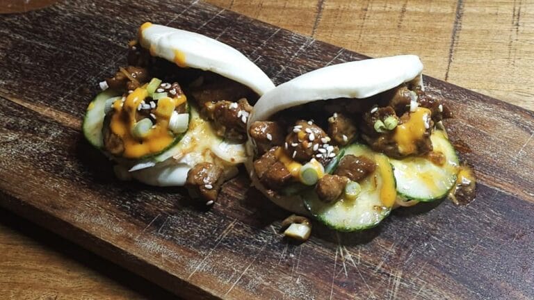 bao buns met zoete kippendijen op een houten plank.