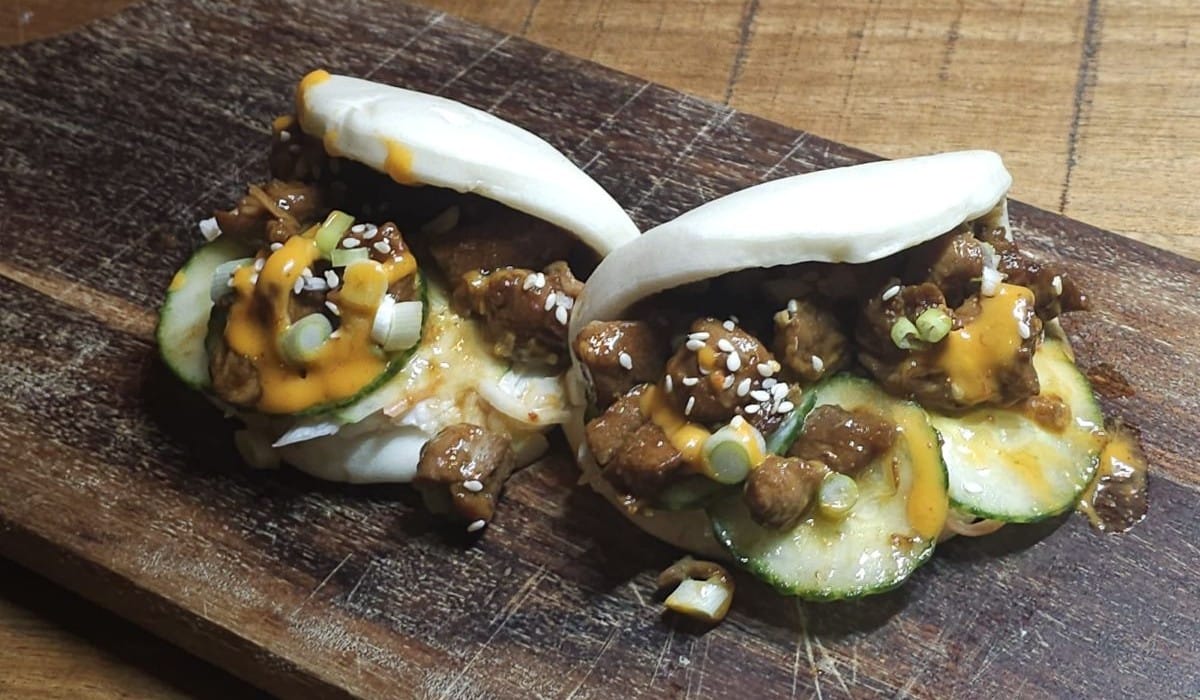 bao buns met zoete kippendijen op een houten plank geserveerd