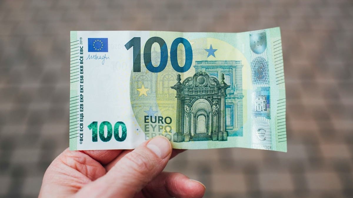 honderd euro in hand van iemand die van ai gebruiktmaakt om te besparen op vaste lasten.