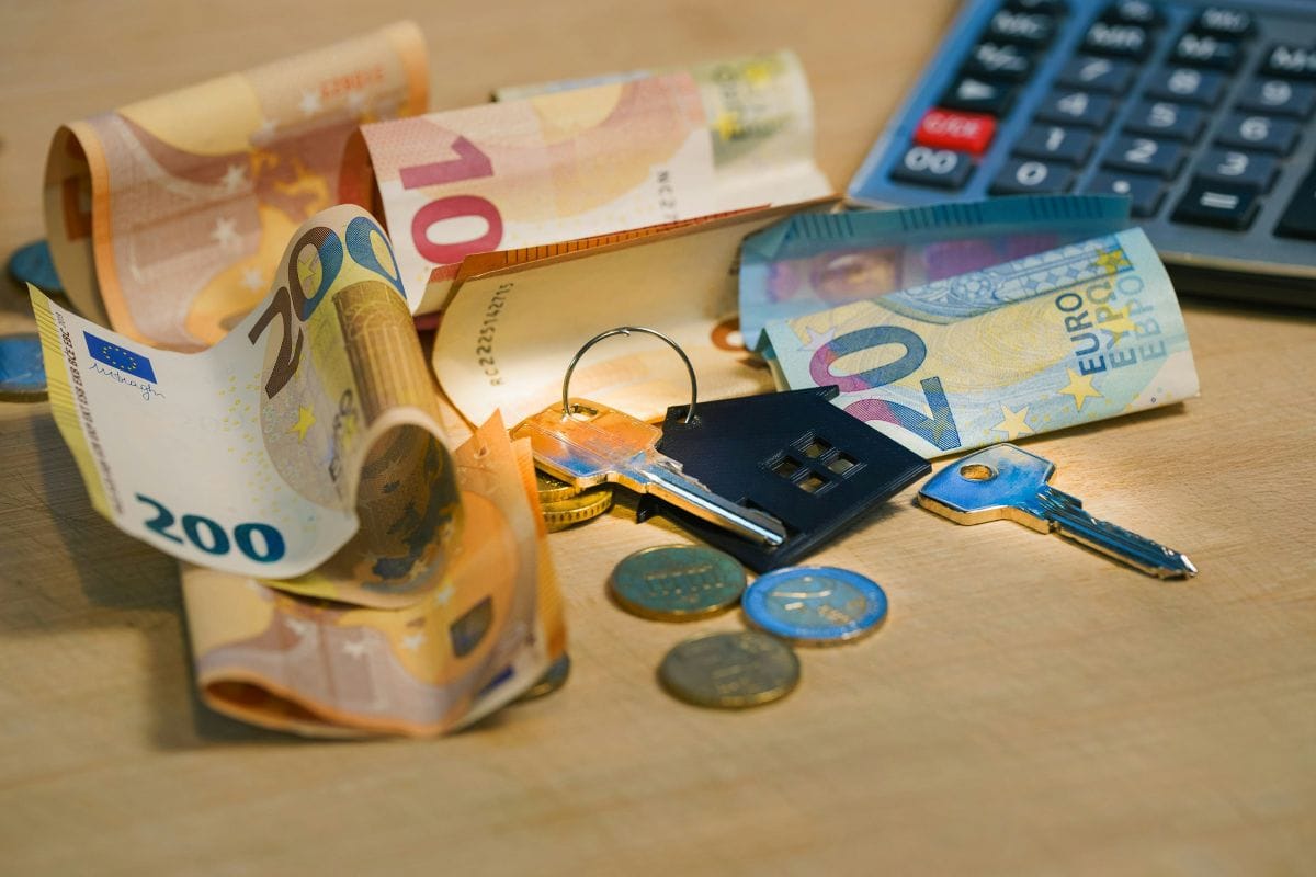 besparen op vaste lasten met geld op tafel en de sleutel van ene woning.