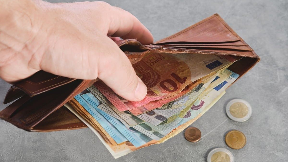 man telst geld in portemonnee dat hij heeft verdiend met doorwerken na aow