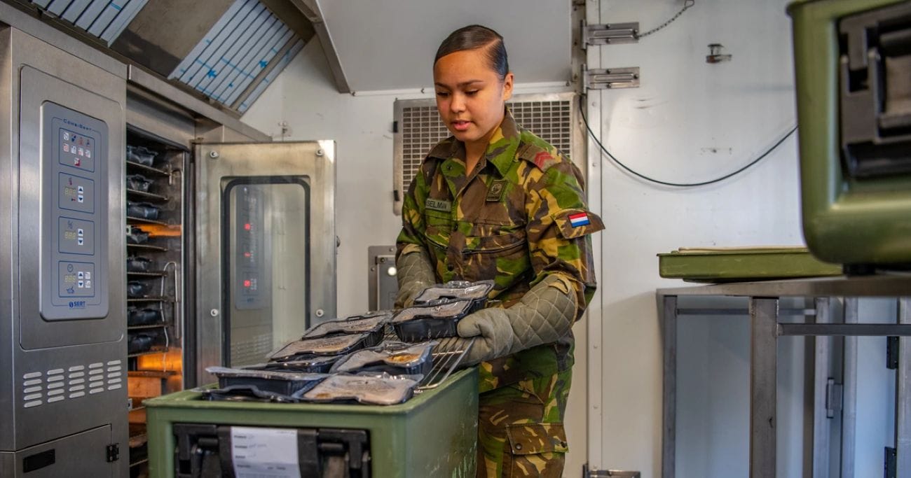 Een soldaat militair kok die eten klaarmaakt voor haar collega's bij Defensie.