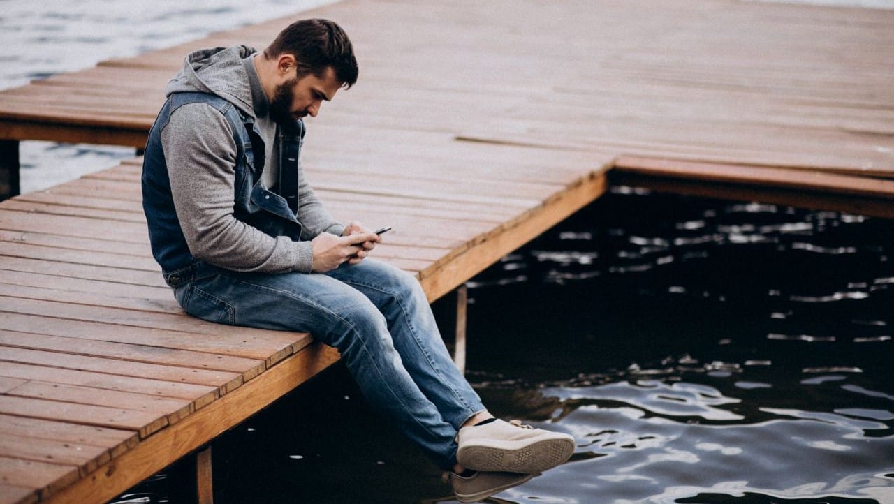 Man zit aan de waterkant te wachten op een reactie van een vrouw die hem negeert.
