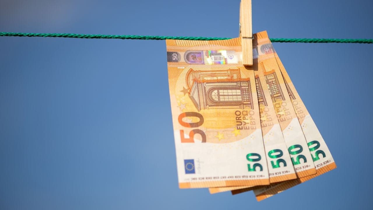 Eurobiljetten aan een waslijn als symbool voor besparen op vaste lasten