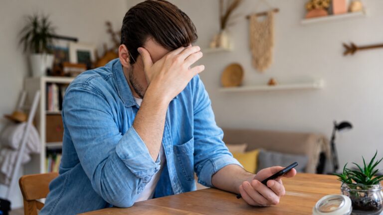 mach kijkt op zijn telefoon omdat zijn salaris te laat betaald is